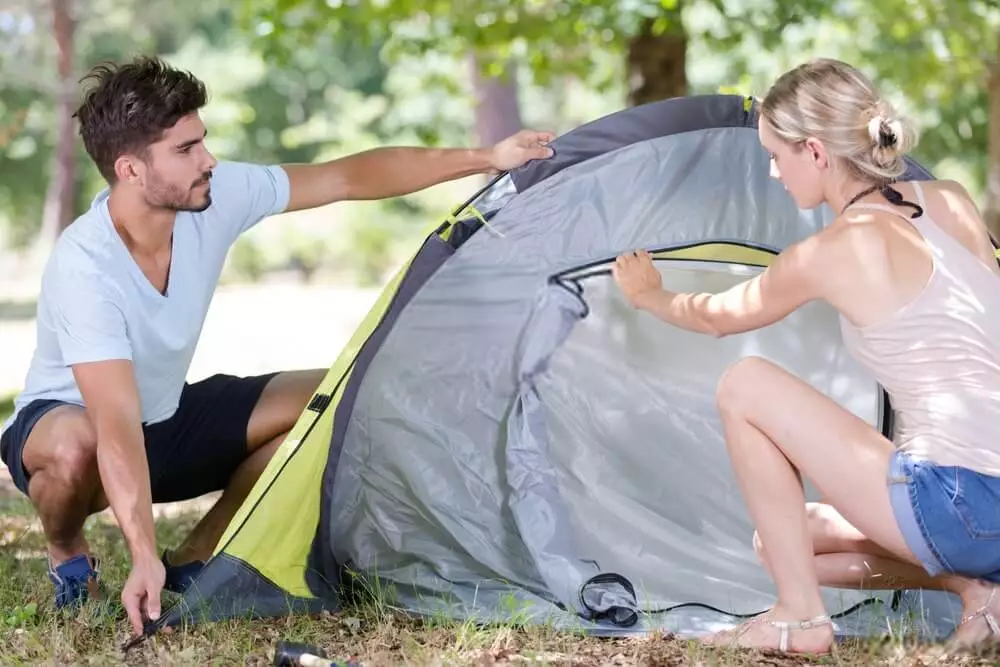 image of male and female inspecting a tent at the campsite while setting up